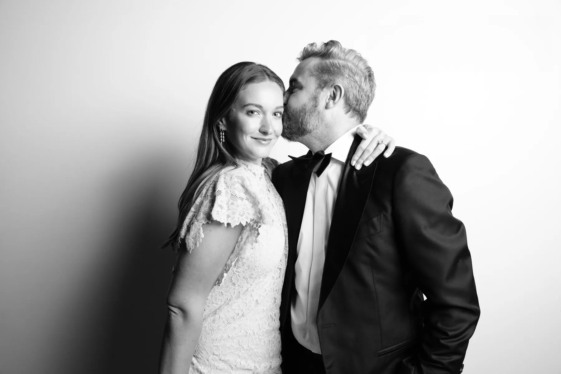A wedding guest leaning in to kiss his partner during their portrait