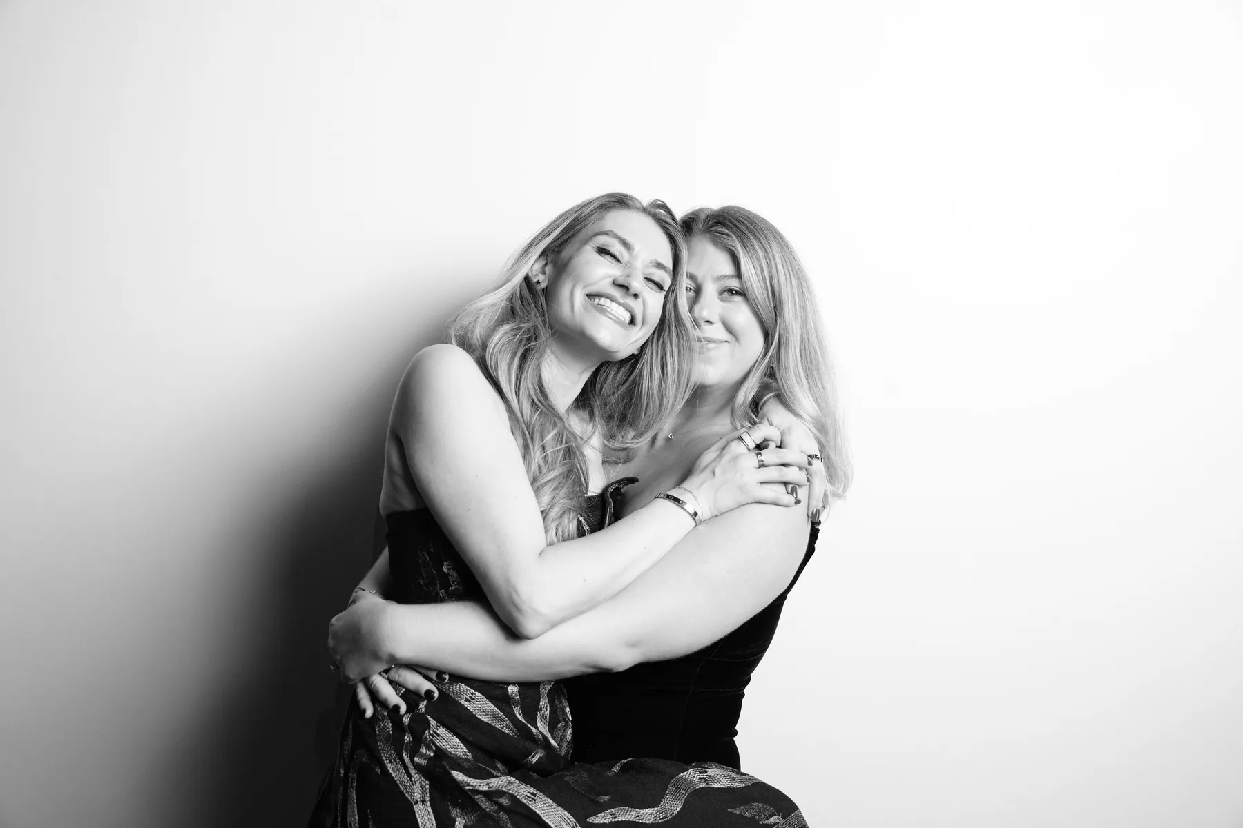 Two wedding guests laughing and embracing for their portrait