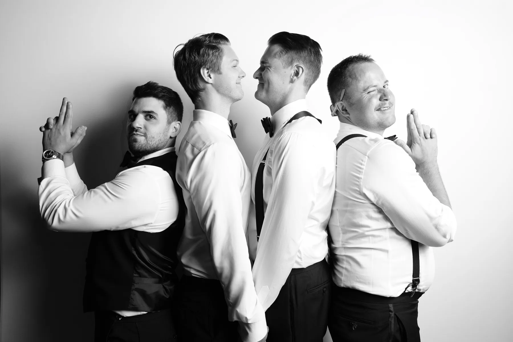 Four wedding guests posing back to back in a playful portrait